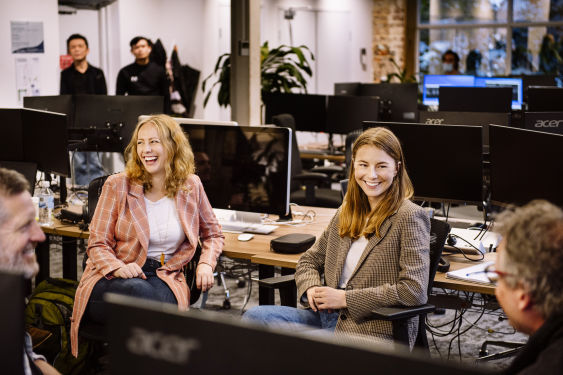 Amelia and Sarah from the Karbon team are smiling at work desks, mid-discussion with Stuart and Ian.