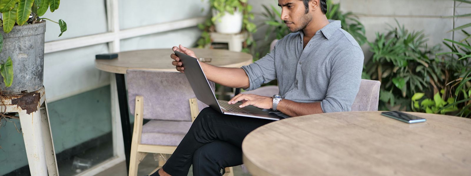 Professional accountant reviewing tasks on a laptop in a relaxed outdoor setting with plants and a rustic decor.