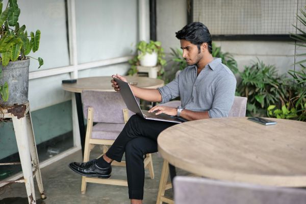 Professional accountant reviewing tasks on a laptop in a relaxed outdoor setting with plants and a rustic decor.