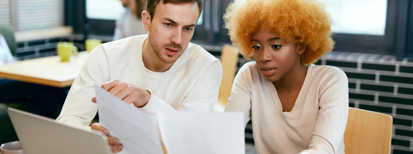 Two accounting professionals review a bookkeeping onboarding checklist together in a well-lit office, with a laptop and documents on the table to ensure a thorough client onboarding process.