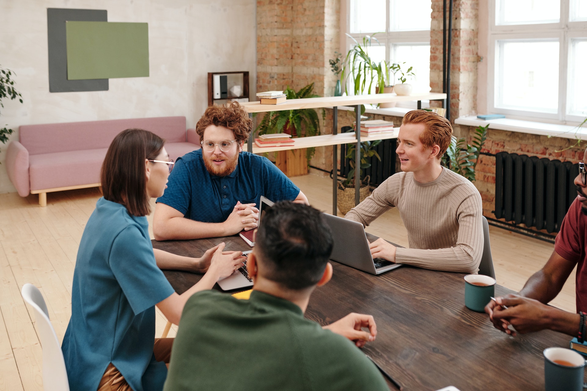A group of millennial-aged colleagues sitting around a table min-discussion.