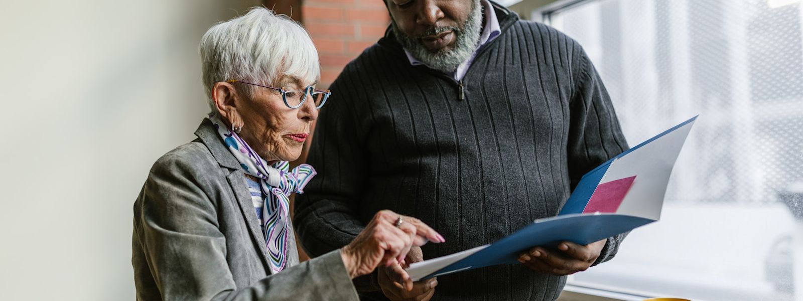 Two people are standing next to each other, looking at an open folder.