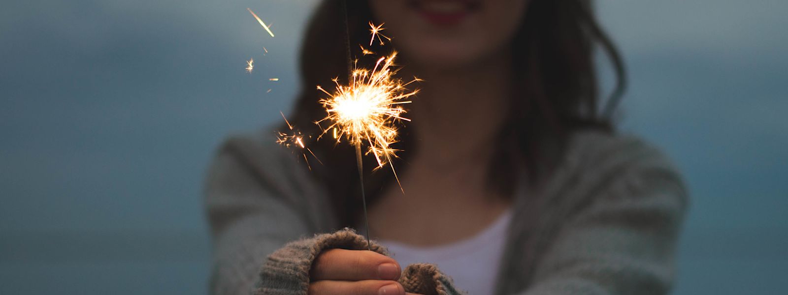 A smiling woman holds a sparkler