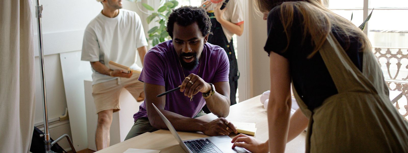 A diverse group of accounting professionals collaboratively working in a bright office, with one focused individual using a laptop to provide outsourced client accounting services.