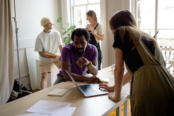 A diverse group of accounting professionals collaboratively working in a bright office, with one focused individual using a laptop to provide outsourced client accounting services.