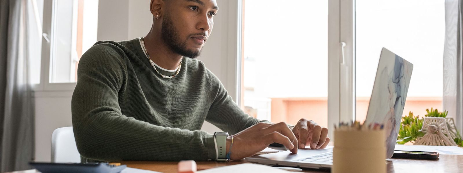 A focused accounting professional evaluating project management software on a laptop in a well-organized workspace.