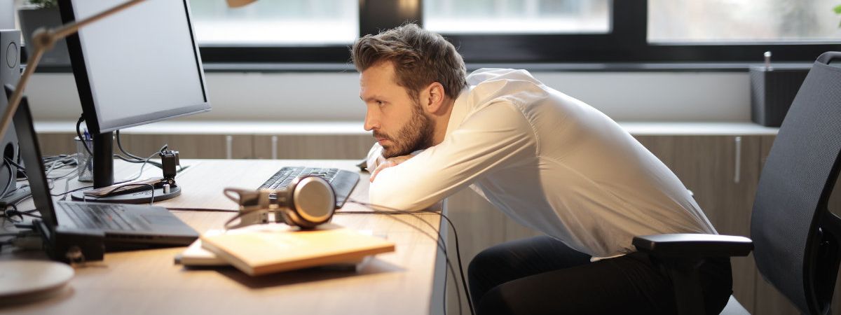 A person slumped at their desk, looking burnt out and uninspired.
