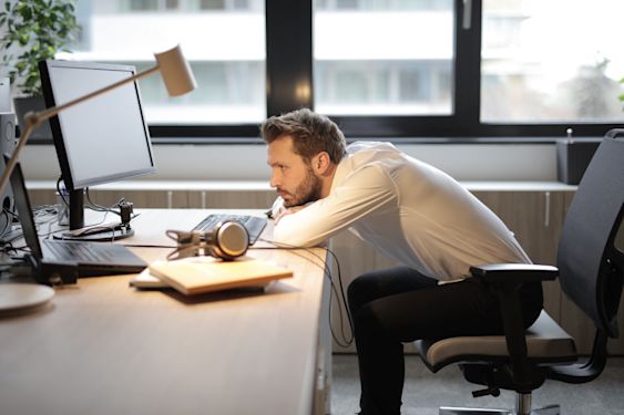 A person slumped at their desk, looking burnt out and uninspired.