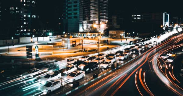 A traffic jam at night. The lanes that are bottlenecked have cars bumper-to-bumper, but the free flowing lanes are lit by headlights captured with a slow shutter.