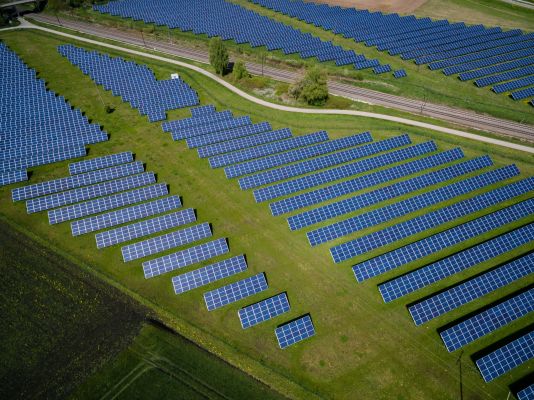 An arial view of a solar panel farm on top of a green field.