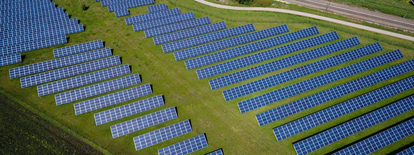 An arial view of a solar panel farm on top of a green field.