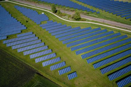 An arial view of a solar panel farm on top of a green field.