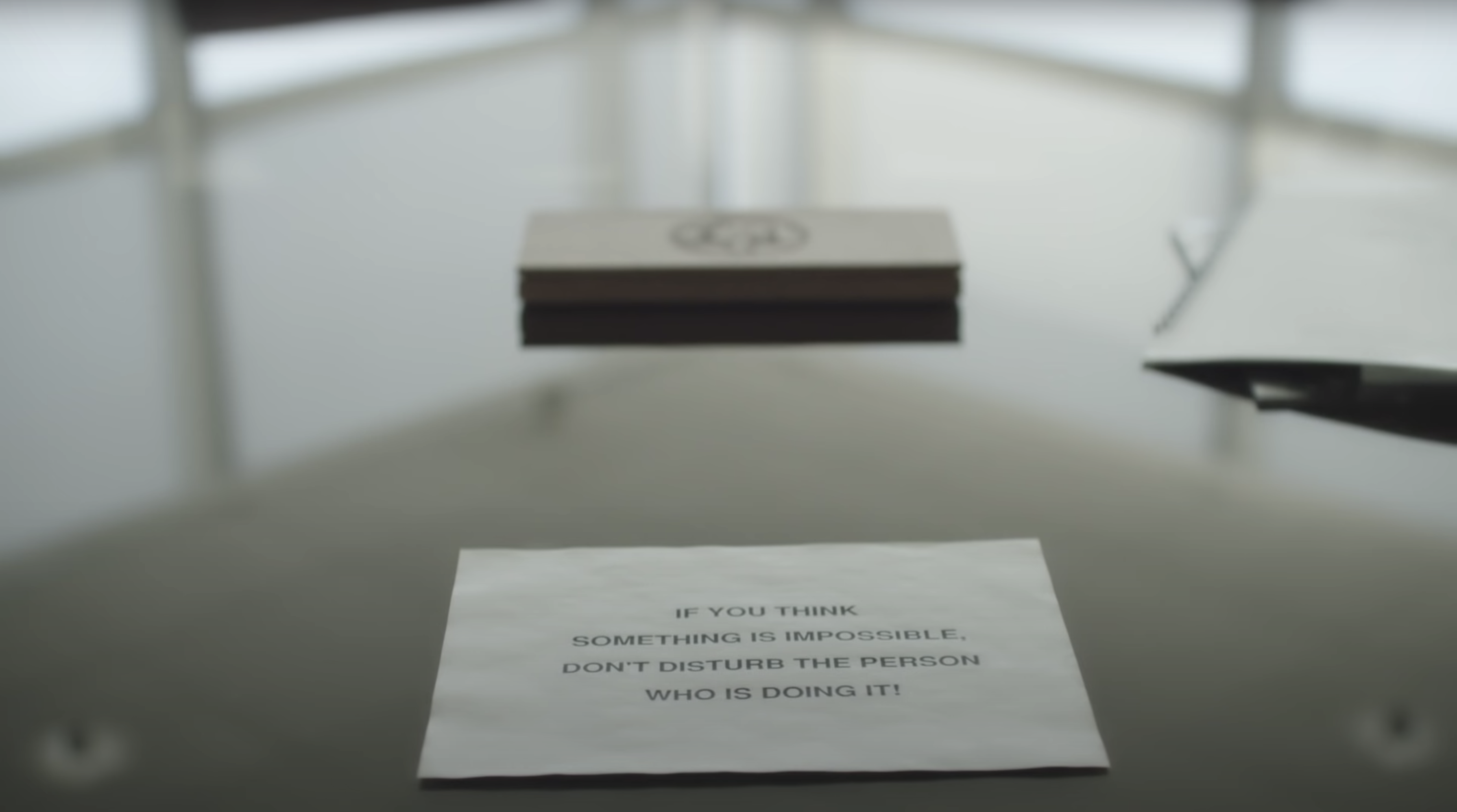 An image of a piece of paper on a desk with the words: “If you think something is impossible, don’t disturb the person who is doing it!”