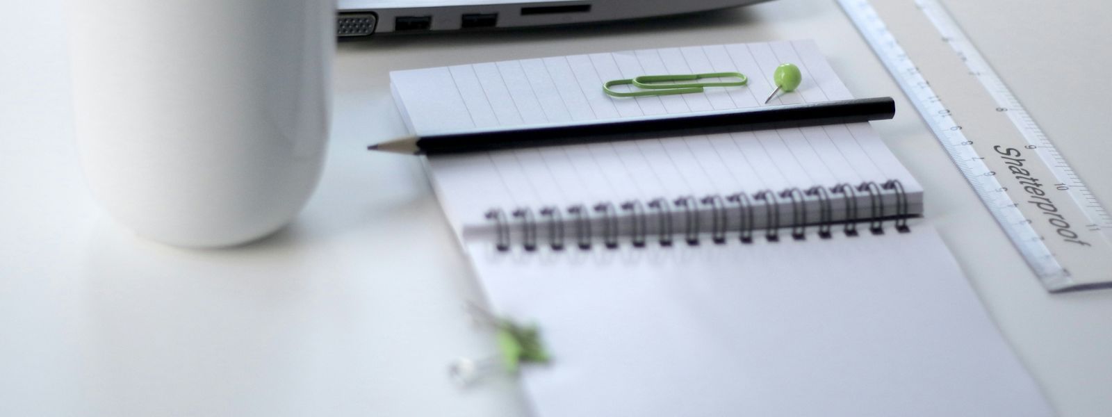 Coffee cup, notebook and laptop on a desk