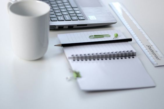 Coffee cup, notebook and laptop on a desk