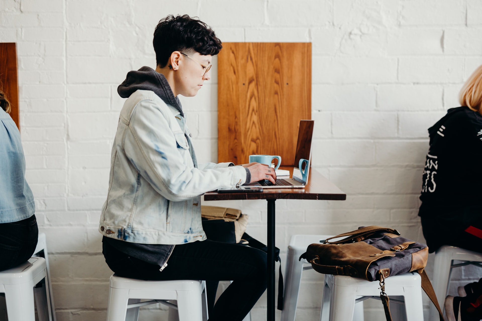 A person is sitting at a cafe table and is working on their laptop