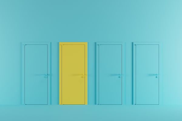 A light blue wall with four doors in a row, the first is the same colour blue, the second is bright yellow, and the third and fourth are blue again.