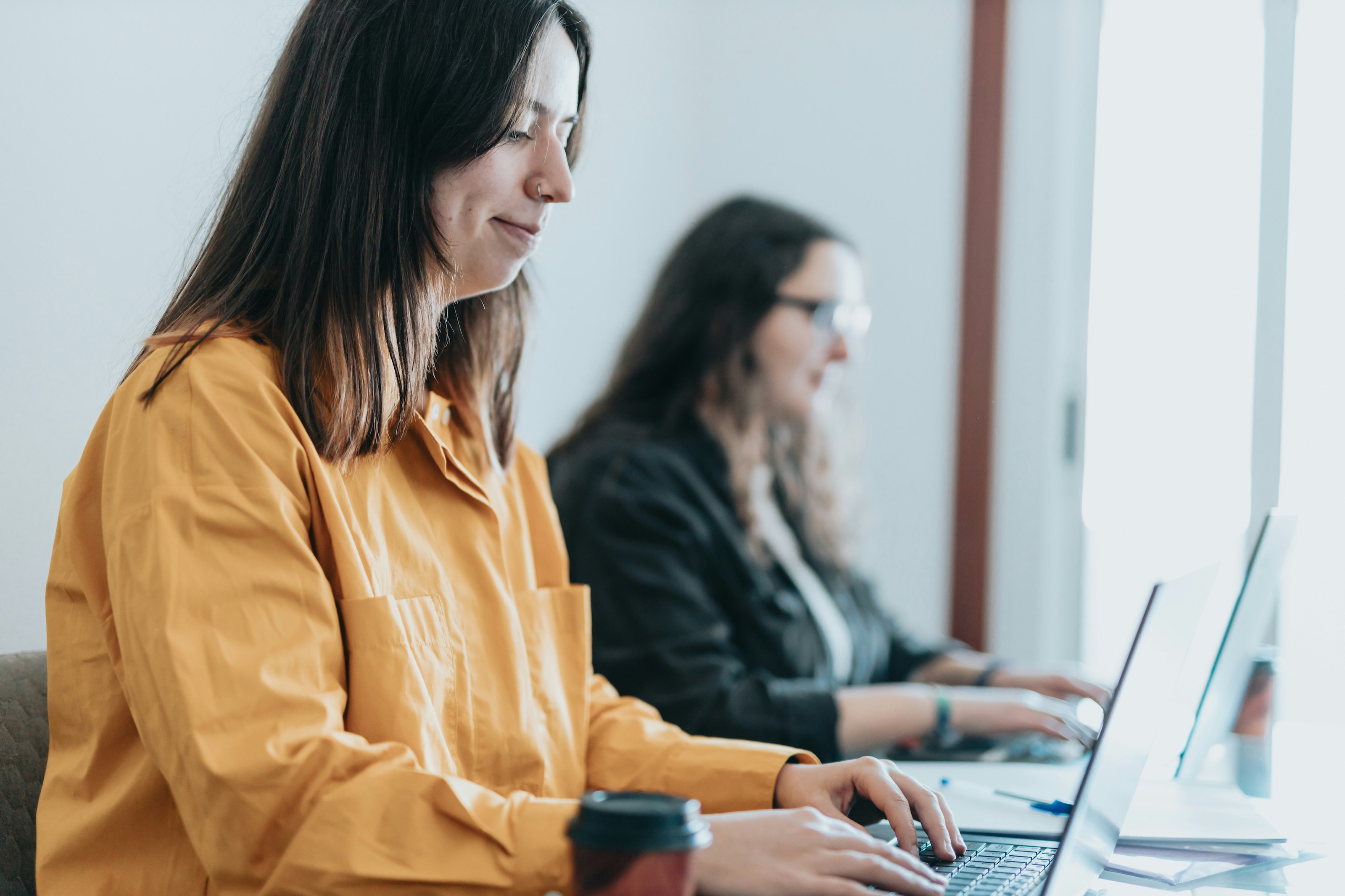 Two accounting professionals focused on their laptops, meticulously working through a month-end close process checklist template to ensure accurate financial reporting.