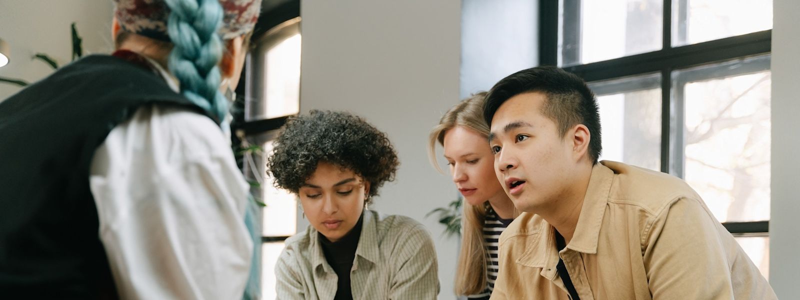 Four colleagues in an office engaged in a meeting, illustrating collaborative efforts in understanding private equity in accounting.