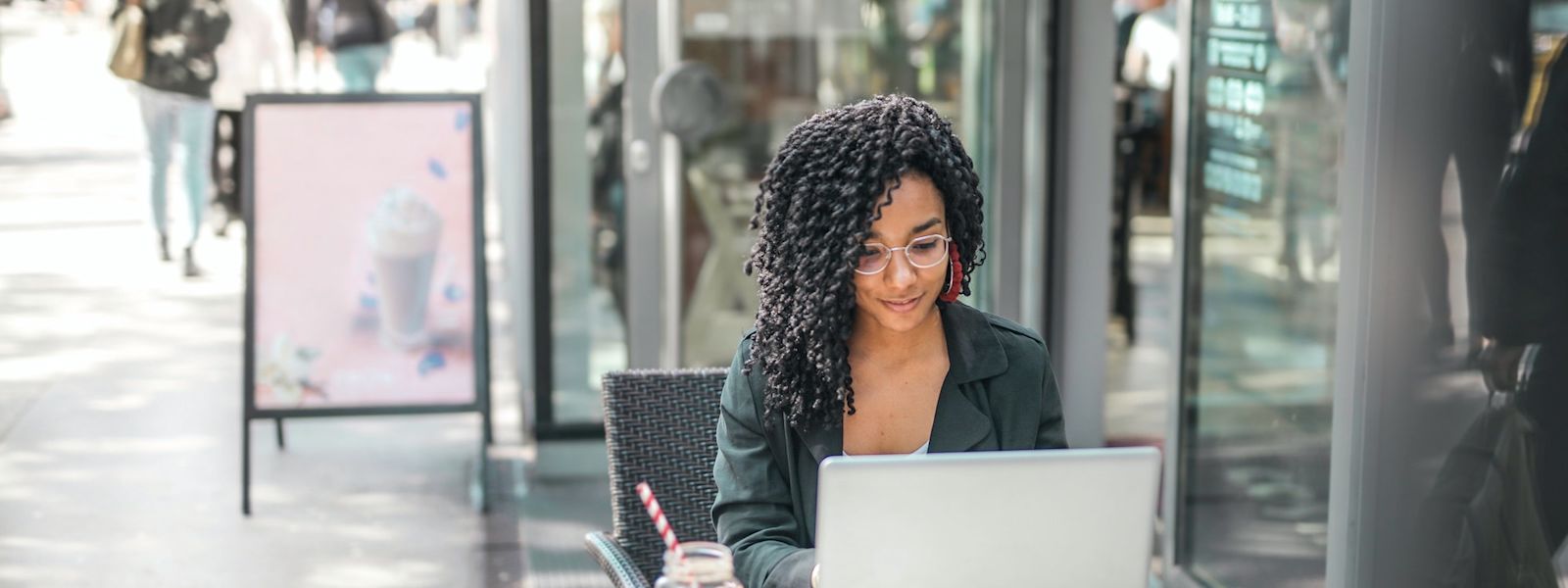 Someone is sitting at an outdoor cafe table, typing on a laptop.
