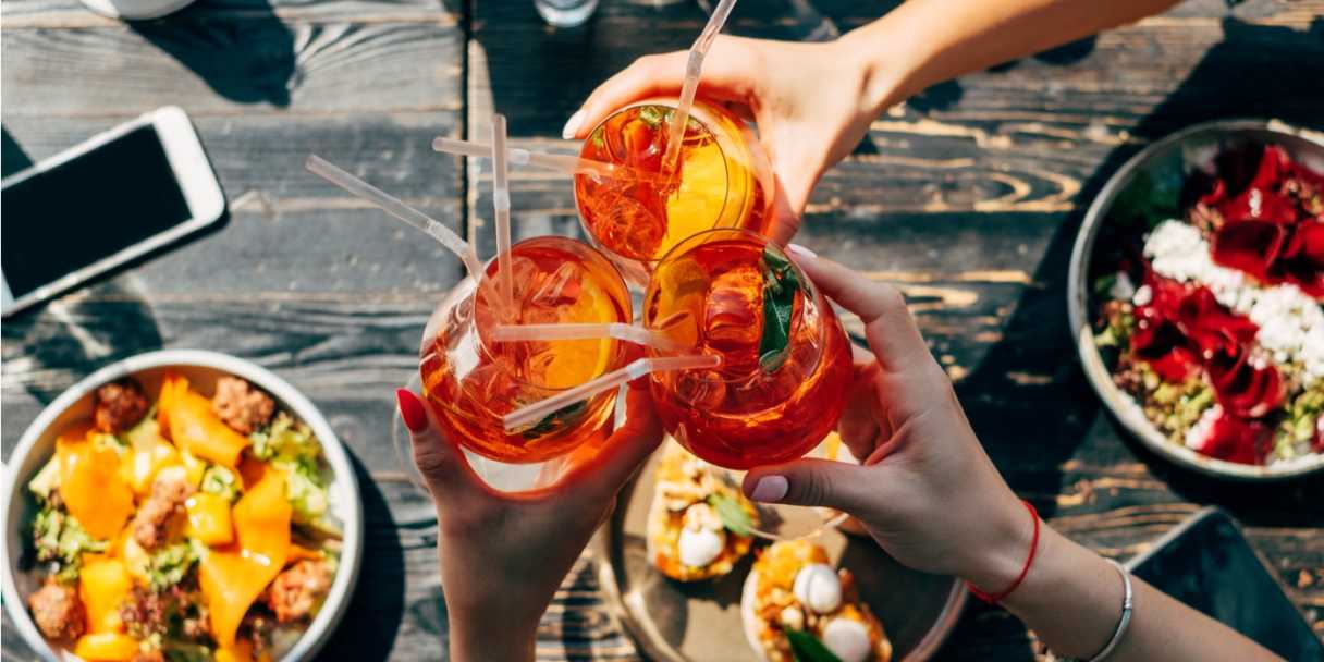 Friends toasting with Aperol spritzes over bottomless brunch in Melbourne