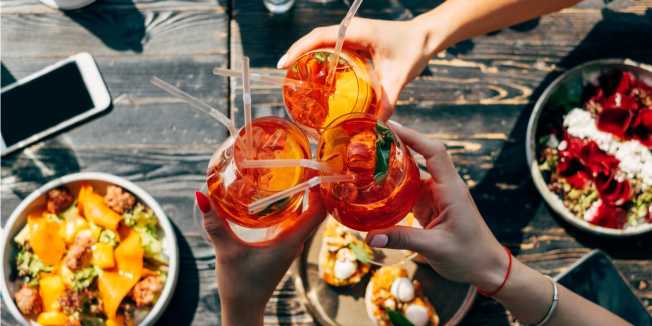 Friends toasting with Aperol spritzes over bottomless brunch in Melbourne