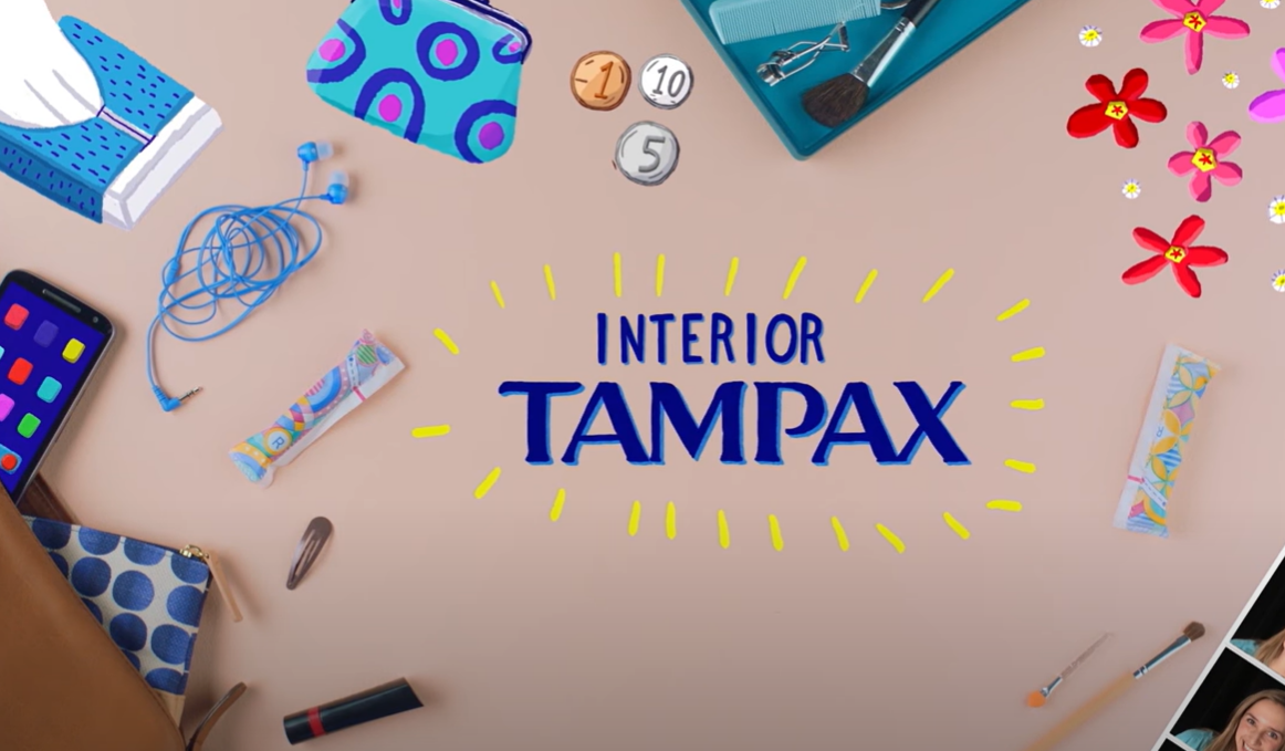 Un texto en el centro del escritorio: Interior Tampax. Hay varios objetos tirados por ahí, como tampones y un teléfono.