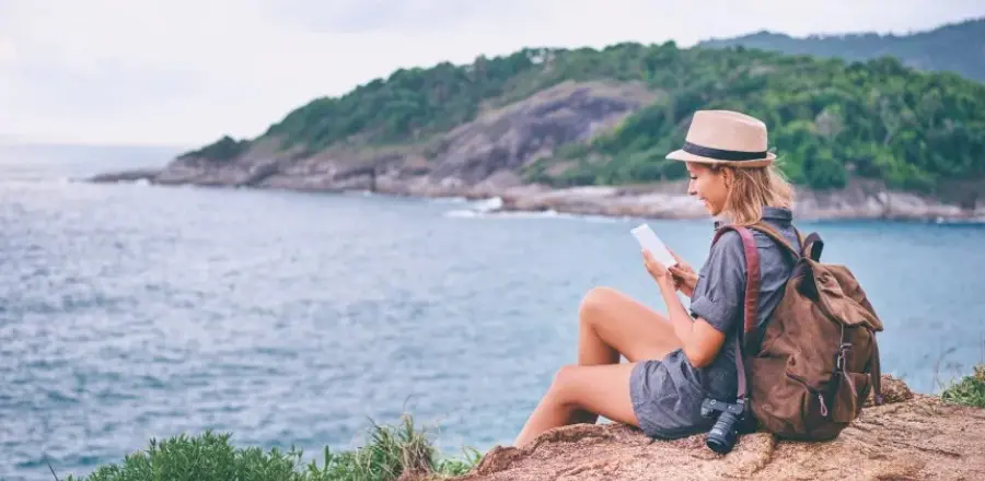 Una mujer sentada en una roca con vistas al mar
