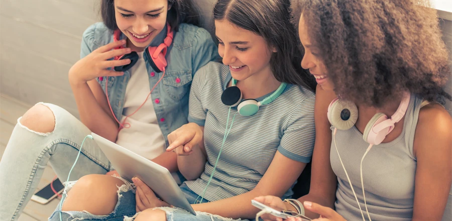 Tres chicas jóvenes mirando algo en la tableta y sonriendo