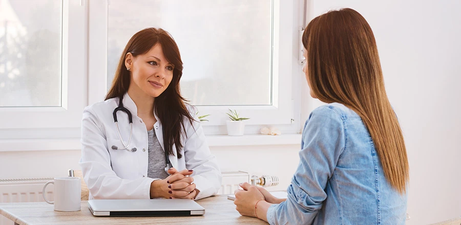 En la consulta de un médico, un paciente habla con un médico. Están sentados uno frente al otro en el escritorio.