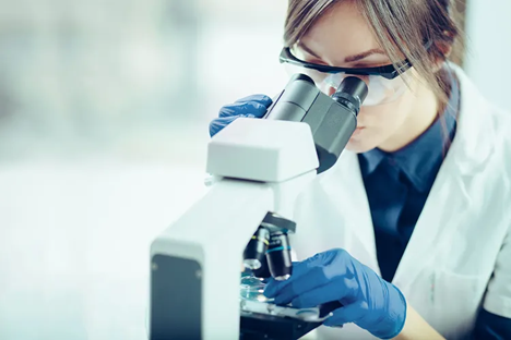 Mujer en un laboratorio mirando por un microscopio