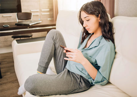 Una mujer mira su teléfono y llena ansiosamente su calendario menstrual