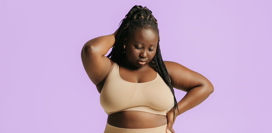 Primer plano de la parte superior del torso y la cabeza de una mujer joven que corre por una playa vacía y sonríe.