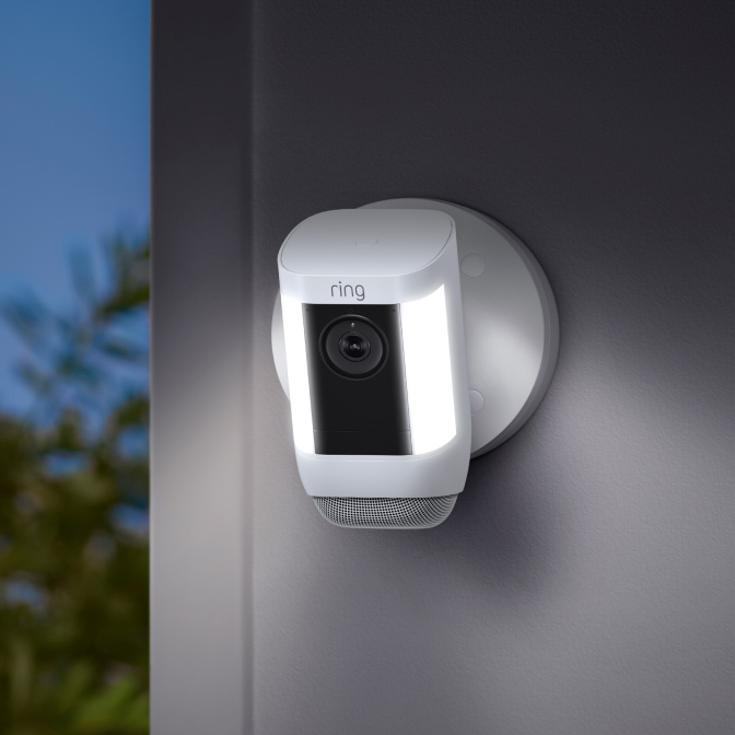 Spotlight Cam Pro blanche fixée au mur avec lumières allumées, prête à filmer en 2K jour et nuit.