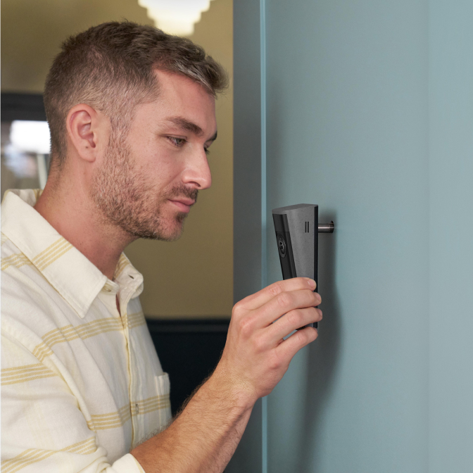 Image showing a man in profile fitting a Peephole Camera 2K into a light blue door.