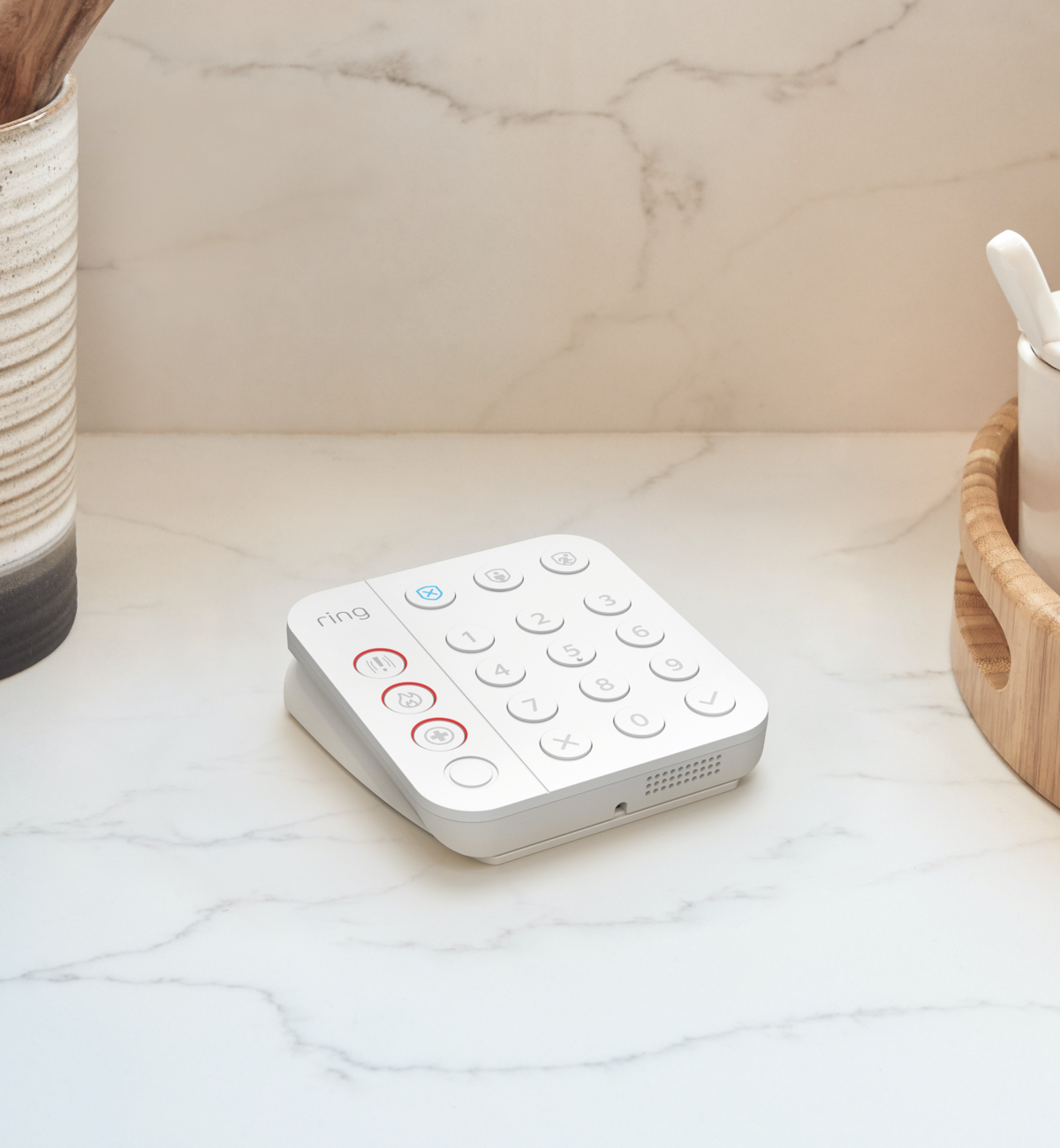 Weißes Ring Alarm Keypad auf Marmorfläche mit beleuchteten Tasten zum Scharf- und Unscharf-Schalten sowie Notfallalarm.