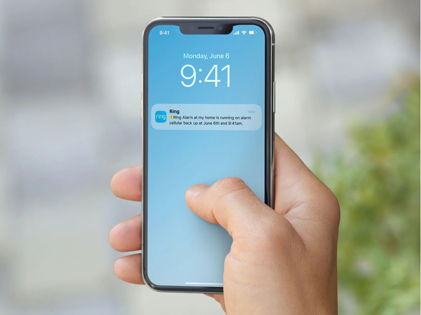 An image of an arm holding a smartphone with a Ring App notification view.