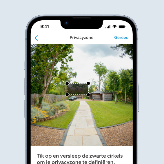 Smartphone toont Ring-app weergave van tuin waarbij gebruiker aanpasbare Privacy Zone instelt over geparkeerde auto.