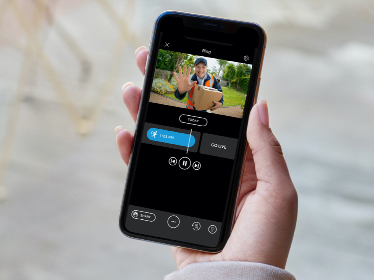 Person views video feed in Ring app showing a delivery person waving at camera.