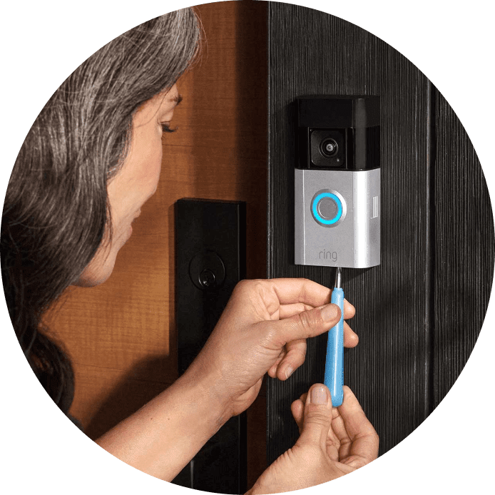 Woman installs Ring Battery Doorbell Pro on door frame using a screwdriver during setup process.