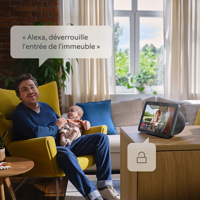 Un père tient son enfant et parle à Alexa.