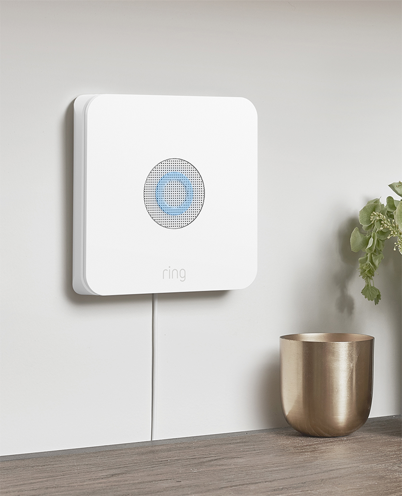 Wall-mounted Ring Alarm Base Station with glowing LED ring, used to manually trigger the siren during emergencies.