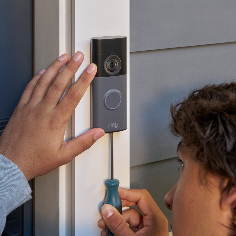 A man installing Ring Video Doorbell next to a door entrance wall.