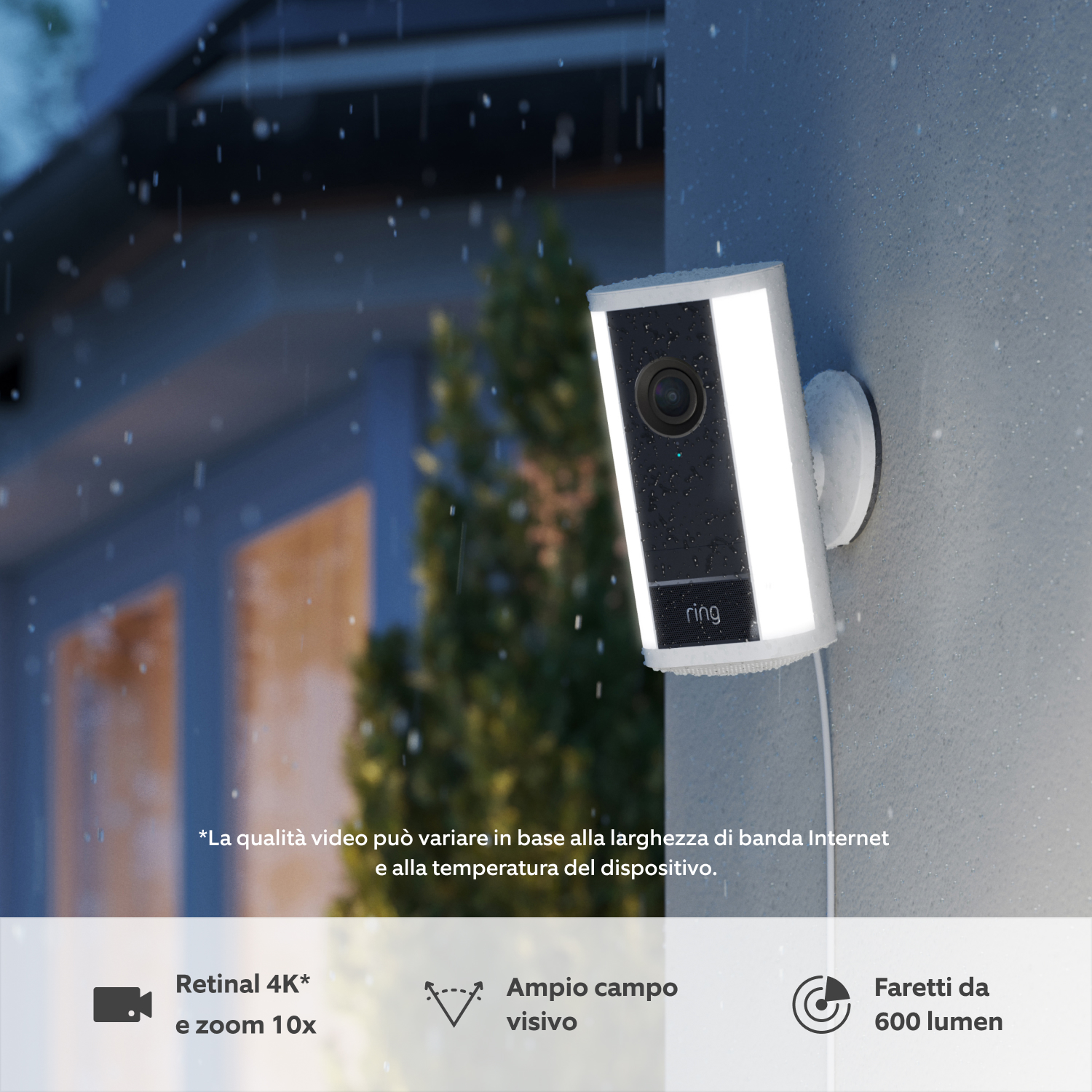 Confezione da 2 Videocamera Pro con faretti (ultimo modello) con alimentatore plug-in (for Spotlight Cam Pro Plug-In (2nd Gen)) - Una videocamera Pro con faretti Ring (ultimo modello) di colore bianco, montata su una parete al tramonto sotto la pioggia, con faretti a LED integrati illuminati