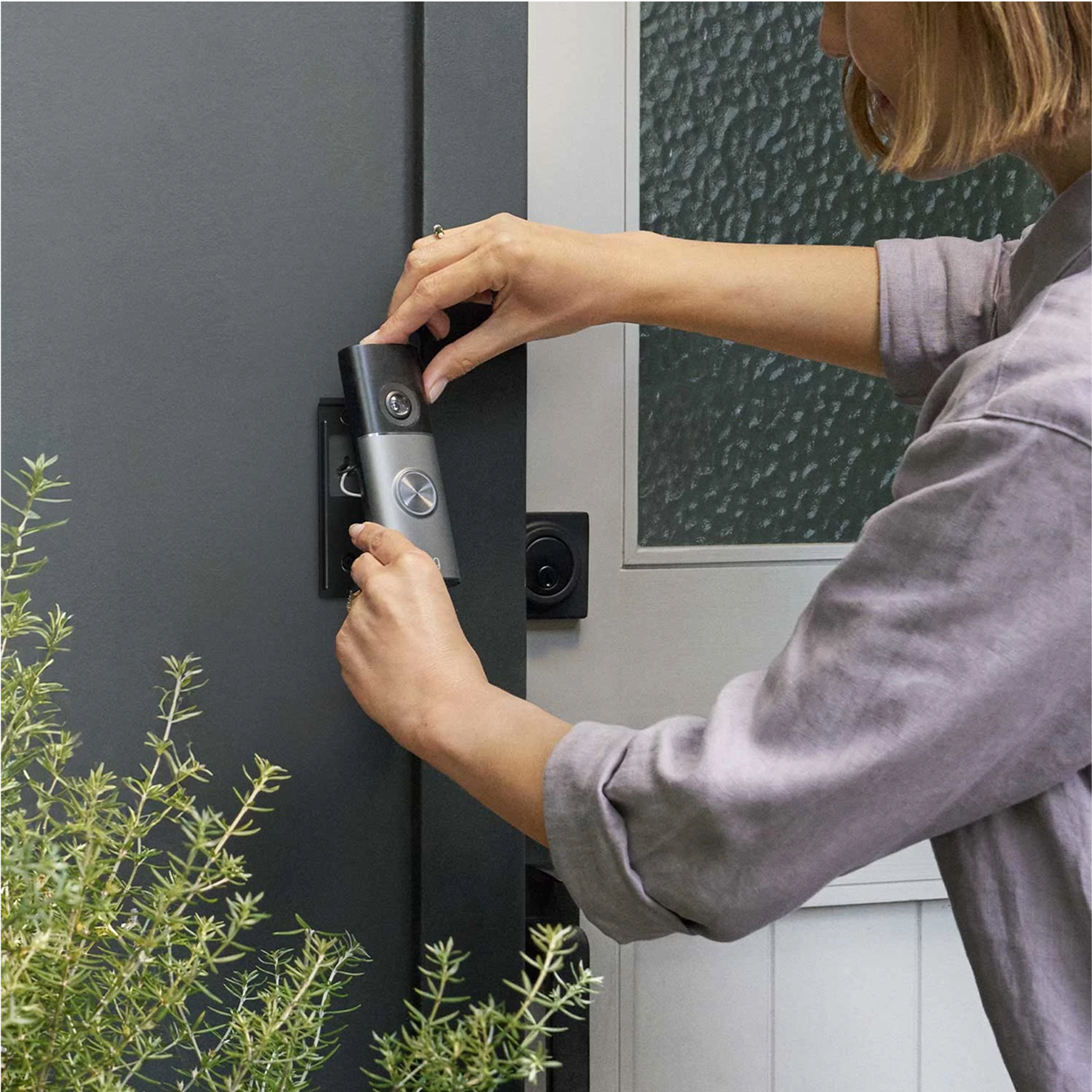 Image shows a lady securing a Wired Video Doorbell Pro (3rd Gen) onto its mounting bracket.