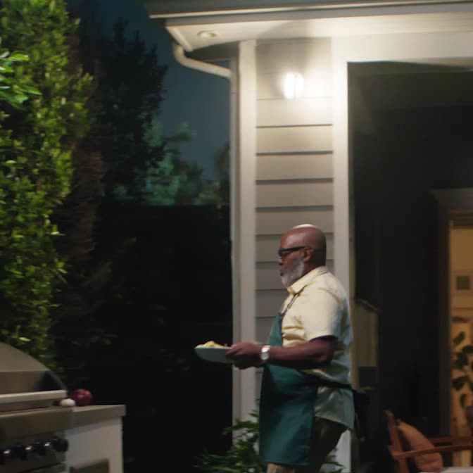 Man walks to his outdoor grill at night. Spotlight Cam Pro (newest gen) illuminates the entire grill area for him.