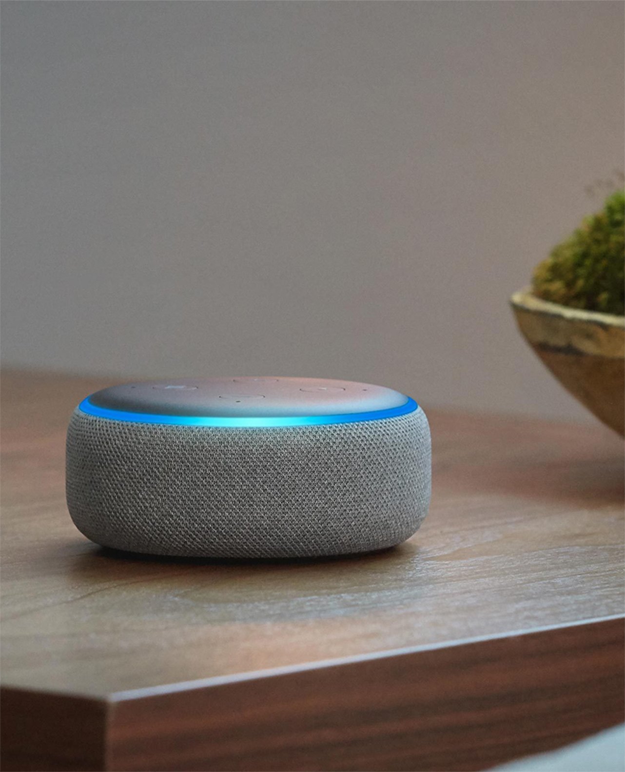 Alexa-enabled smart speaker with blue light ring on wooden table, used to control and monitor Ring Alarm with voice.