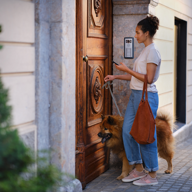Een hondenuitlater krijgt toegang tot de hoofdingang van het gebouw met behulp van de Ring virtuele sleutelfunctionaliteit.