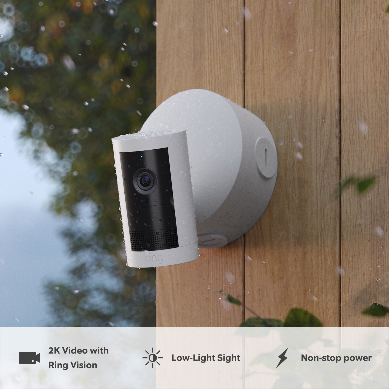 Outdoor Camera Plus with PoE Adapter (Featuring 2K Video with Ring Vision) - White:Ring Outdoor Cam Plus on wood wall, covered in raindrops in rainy weather.