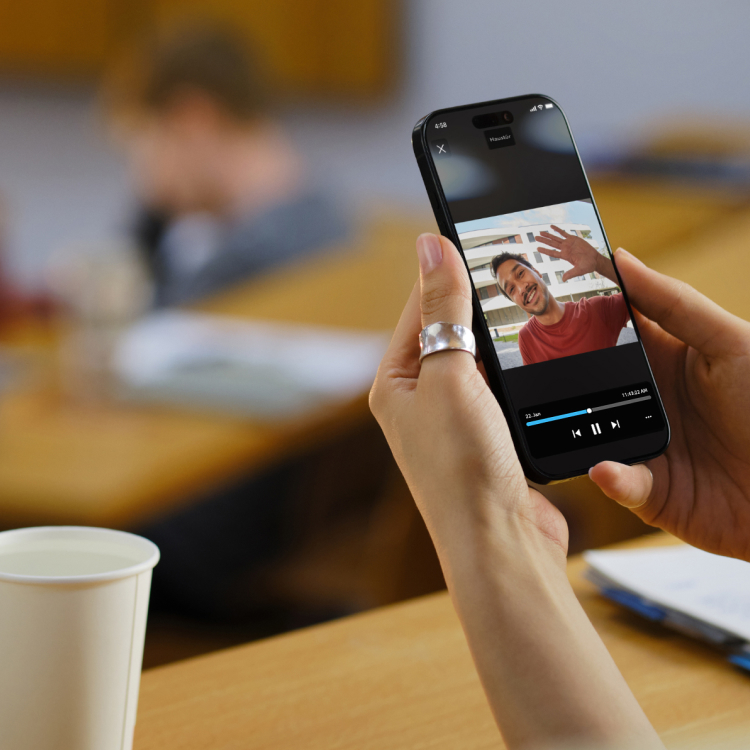 Frau sitzt im Auditorium und hält ein Smartphone mit der Ring App-Ansicht.